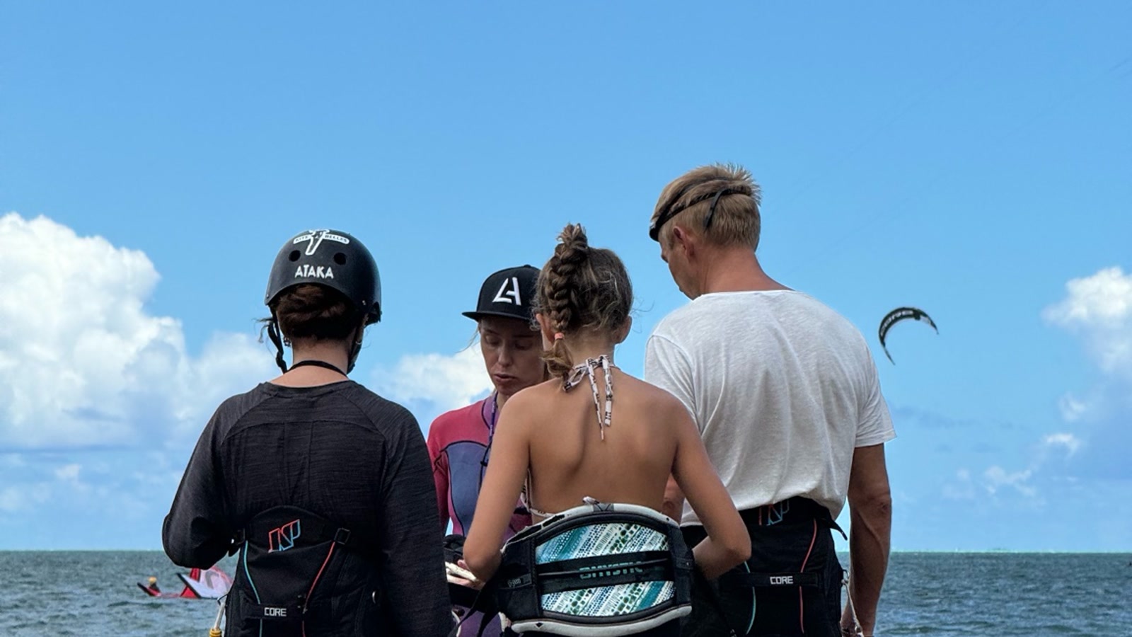 A Kitebelles instructor briefs three students before a kitesurfing lesson in Le Morne