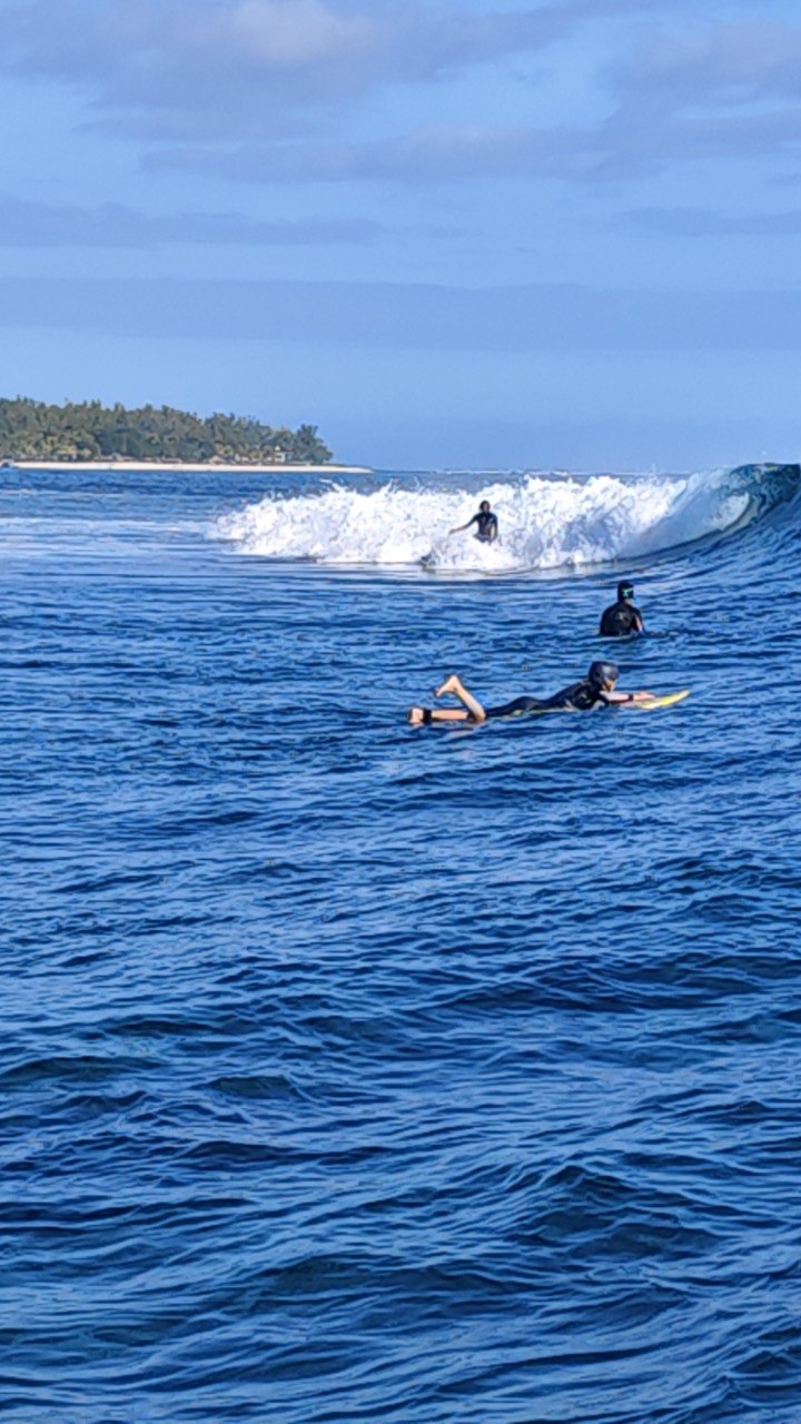 Surfers paddling into waves at Small Reef